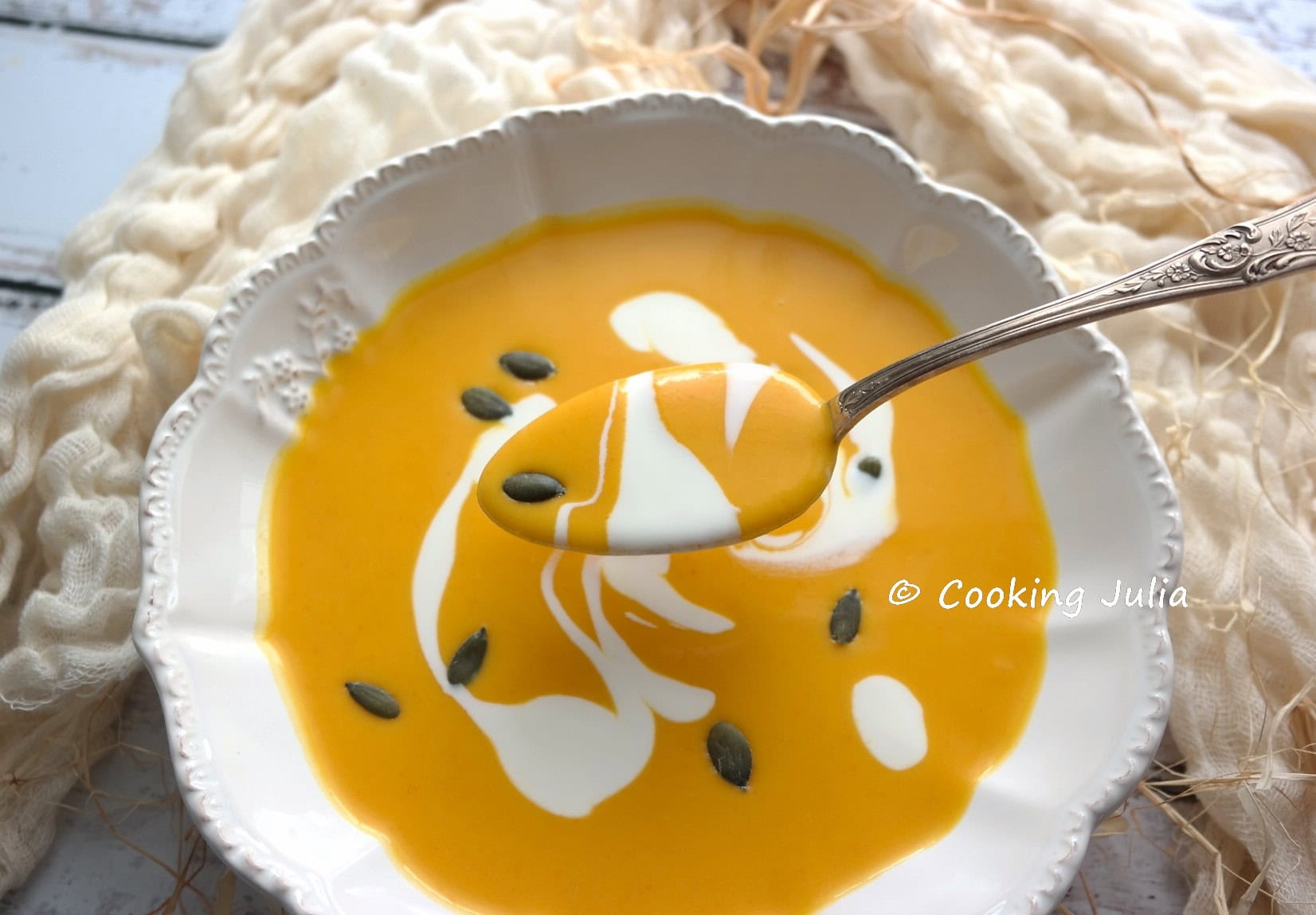 Velouté de potimarron onctueux dans assiette blanche décoré de crème et graines de courge